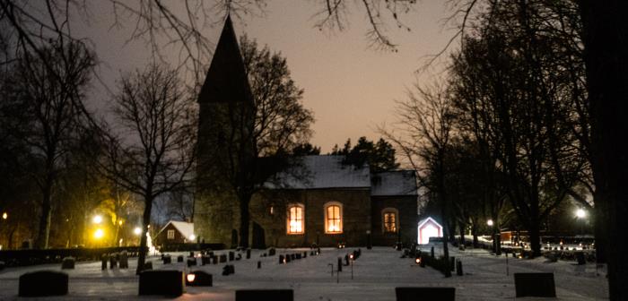 En kyrka lyser i mörkret en vinterkväll.