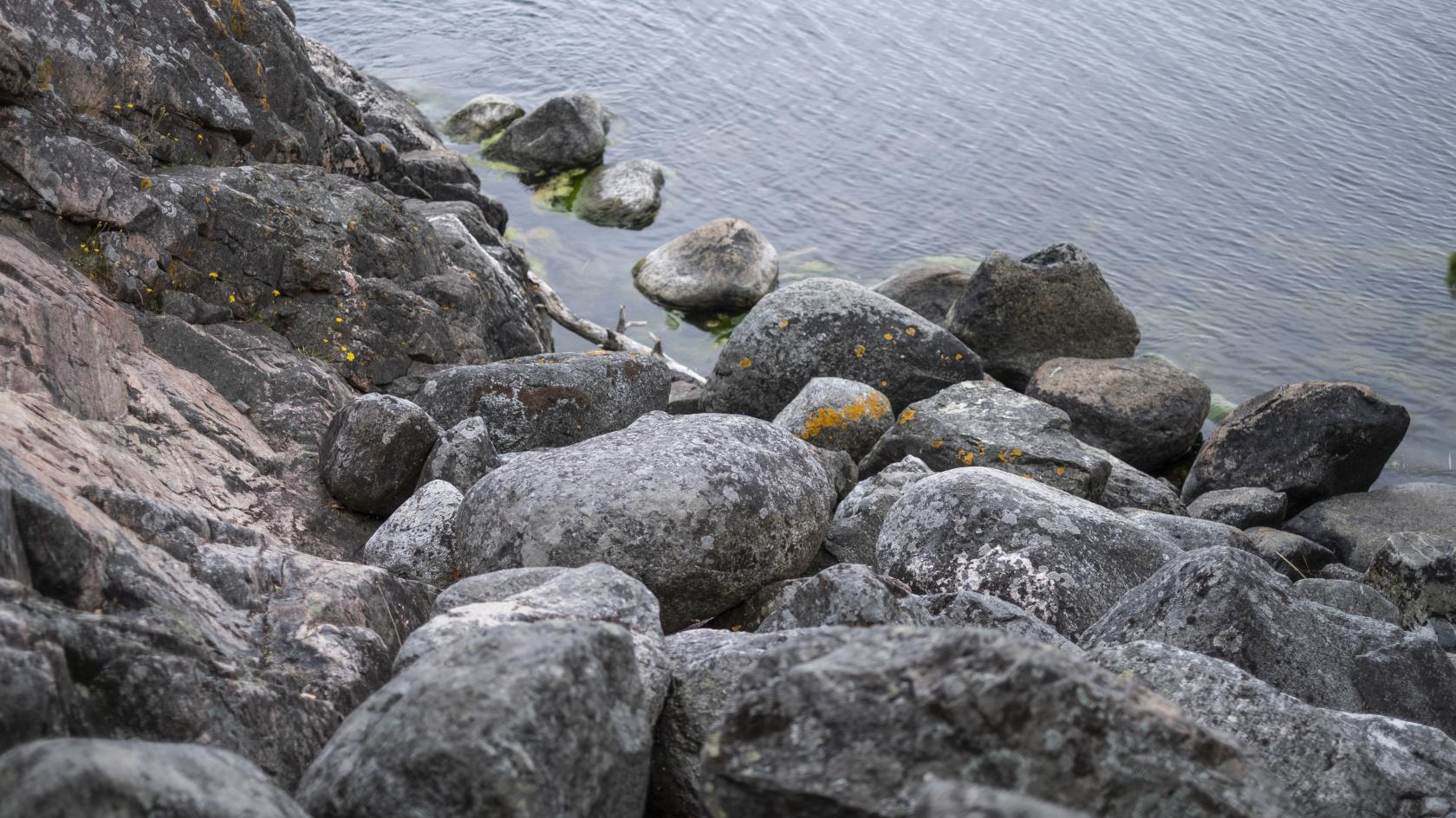 Lösa stenar på klippan ner mot vattnet.