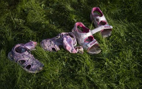 Några rosa sandaler och strumpor ligger i gräset.
