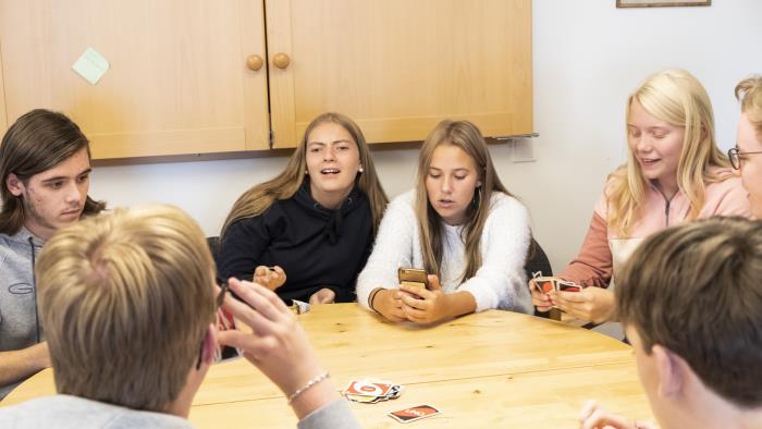 Några ungdomar sitter runt ett bord och spelar Uno.