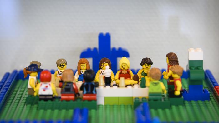 Någon har byggt med Lego: en grupp personer med olika utseenden sitter runt ett långbord.