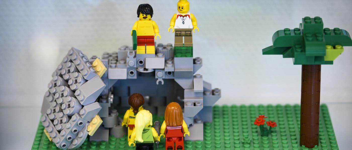 Någon har byggt med Lego: några personer står utanför en tom grotta där dörren vräkts åt sidan.