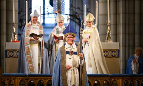 En glad biskop i blå mitra och silverkräkla står i Uppsala domkyrka.