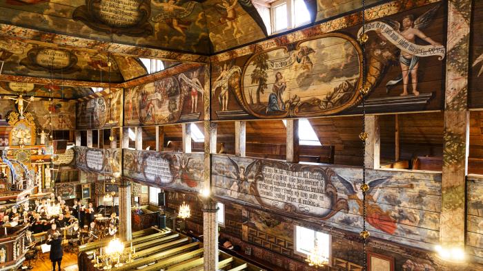En rikligt utsmyckad träkyrka med läktare runt hela kyrkorummet.