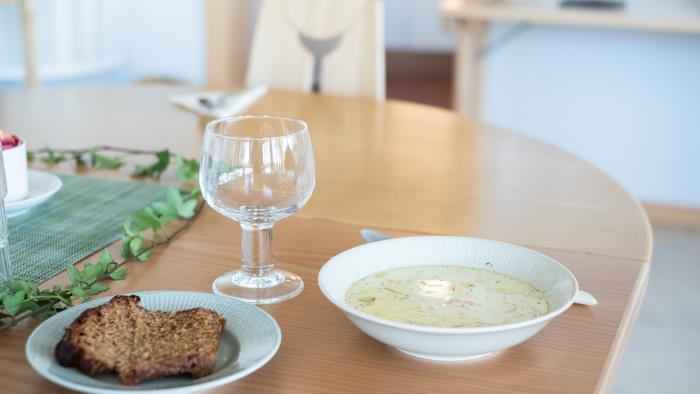 En skål soppa och en brödbit står framdukat på ett bord.