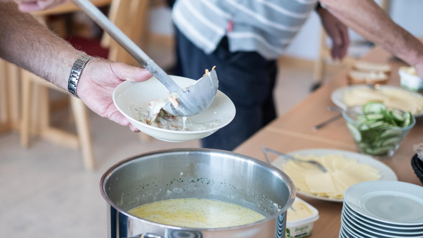 Någon tar en slev soppa ur en kastrull.