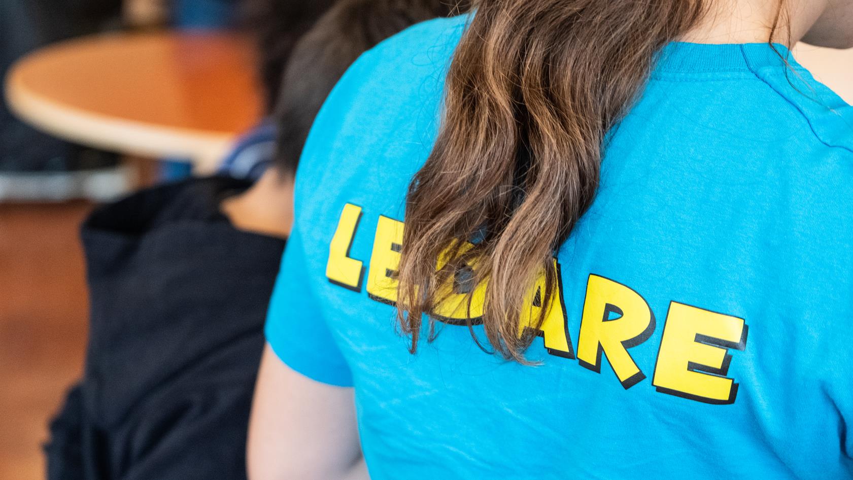 Någon har en blå t-shirt med gula blockbokstäver på ryggen med texten Ledare.