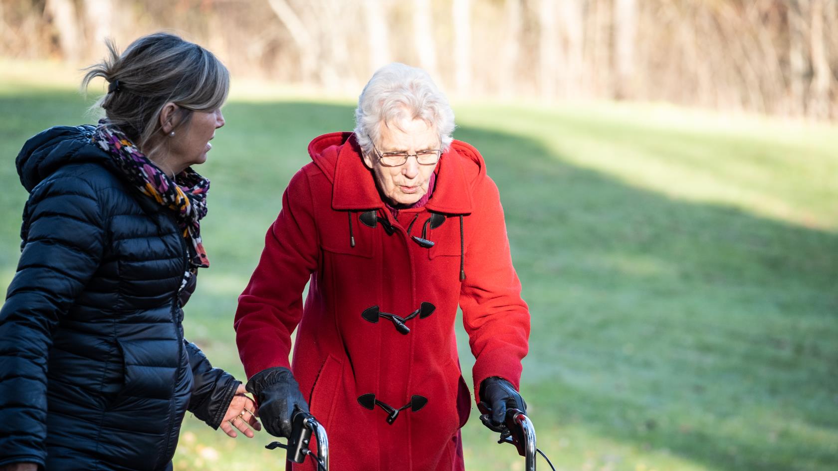 En yngre och en äldre kvinna ute på promenad, den äldre går med en rollator.