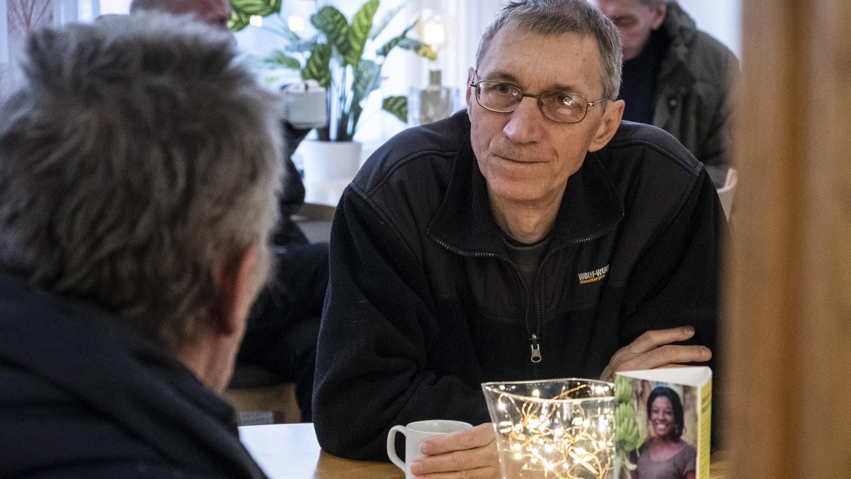 Två män sitter och samtalar över en kopp kaffe.