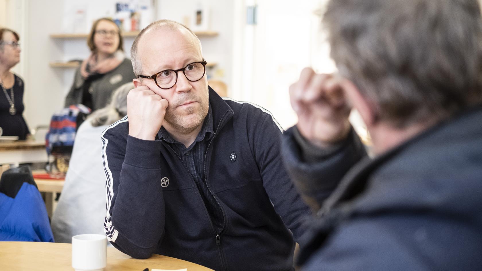 Två män sitter och samtalar över en kopp kaffe.