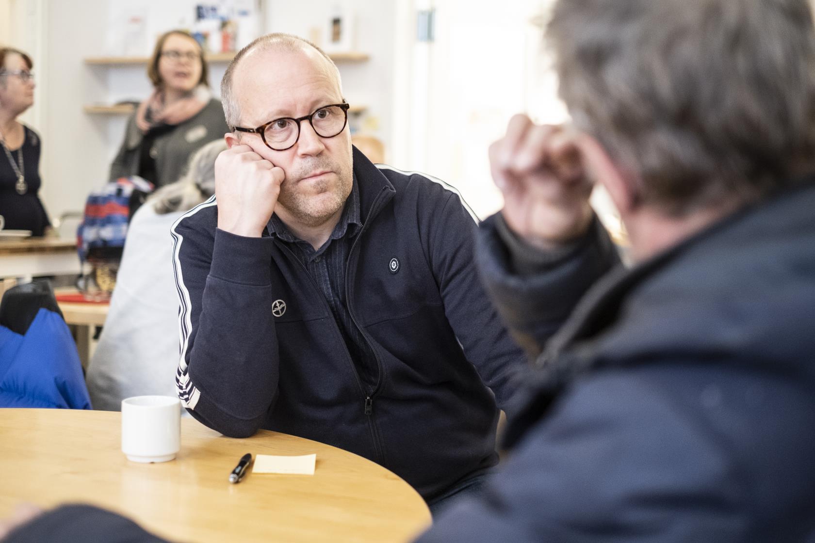 Två män sitter och samtalar över en kopp kaffe.