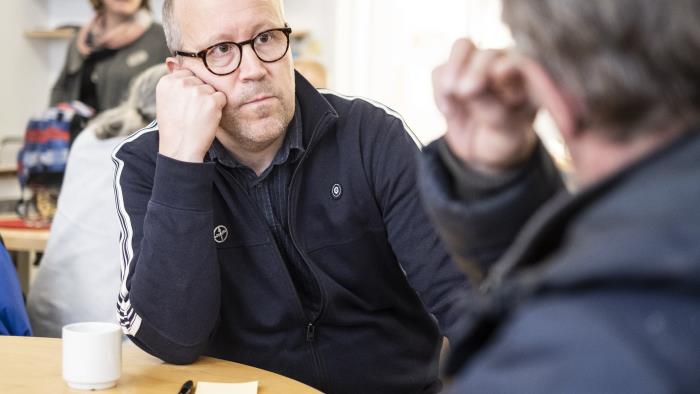 Två män sitter och samtalar över en kopp kaffe.