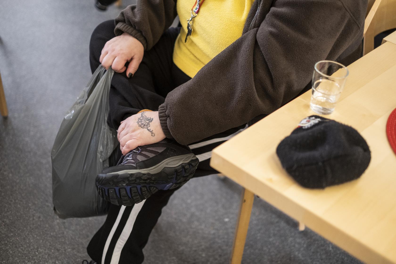 En person med en tatuering på handryggen sitter vid ett bord.