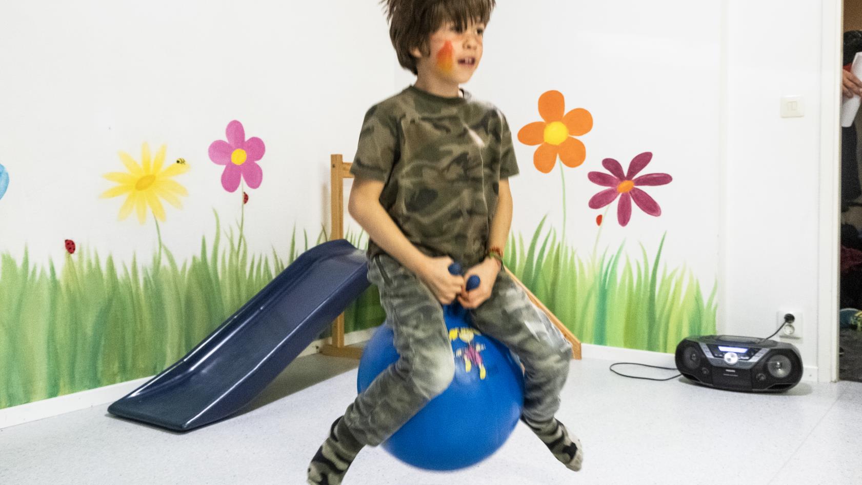 En pojke studsar runt i lekrummet på en blå hoppboll.