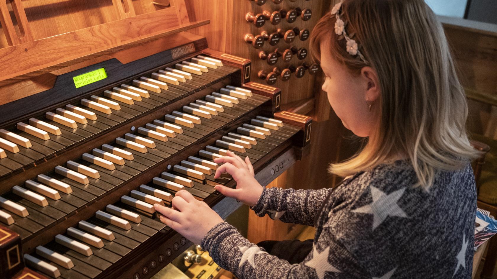 En tjej spelar på en kyrkorgel.