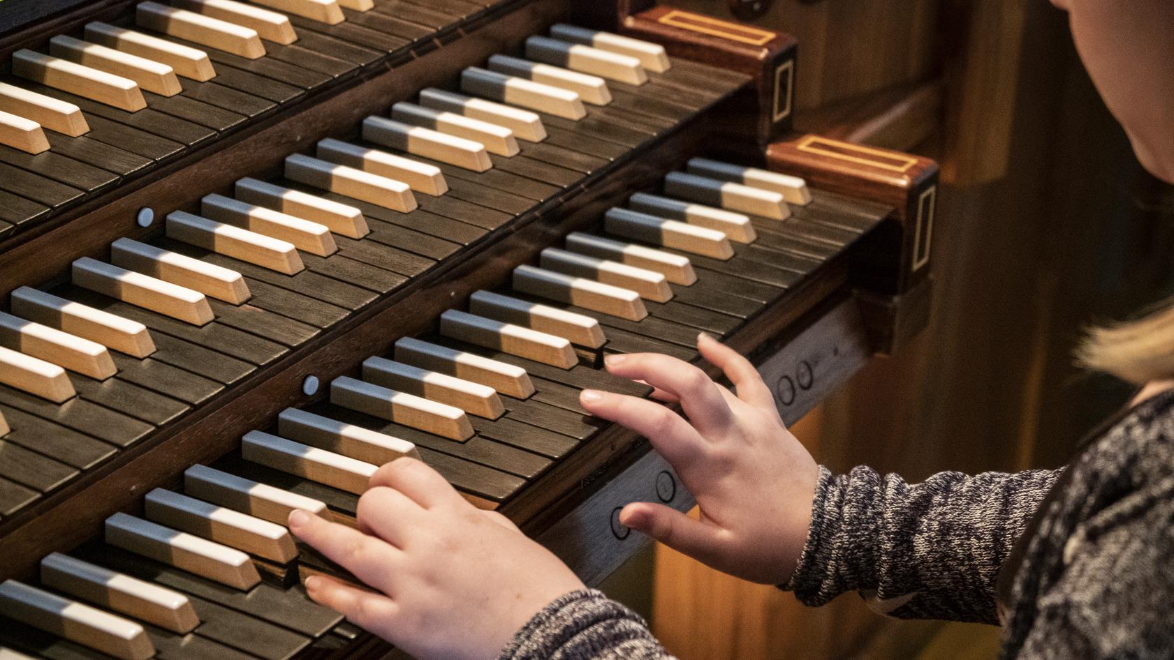 Barnhänder som spelar på en kyrkorgel.