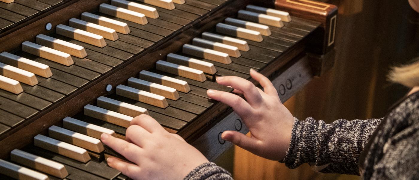 Barnhänder som spelar på en kyrkorgel.