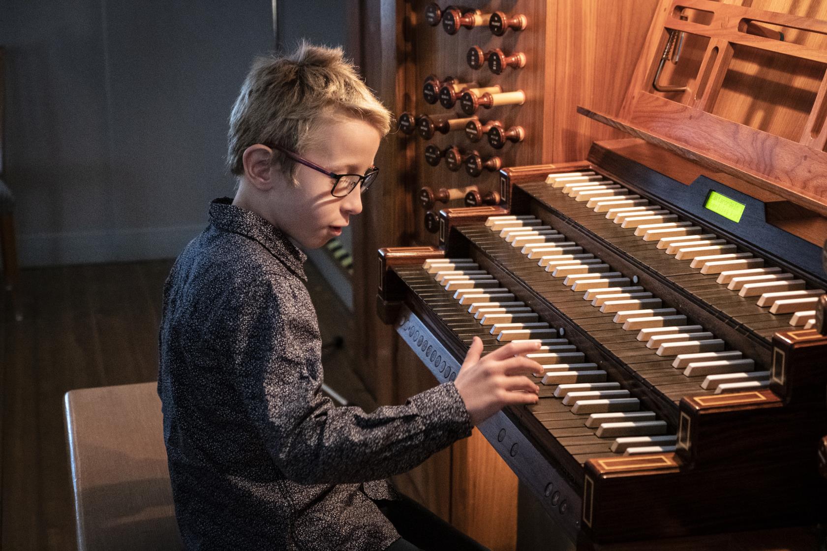 En pojke spelar på en kyrkorgel.