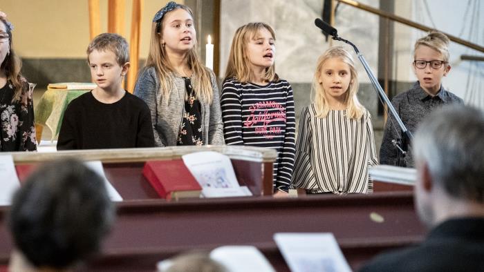 Några barn står bredvid varandra och sjunger framme i kyrkan.