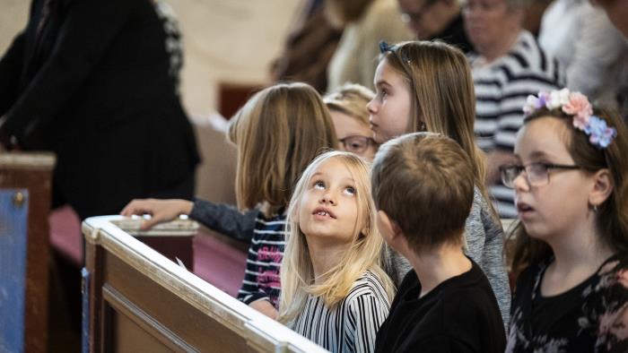 Några barn sitter i bänkraden längst fram.