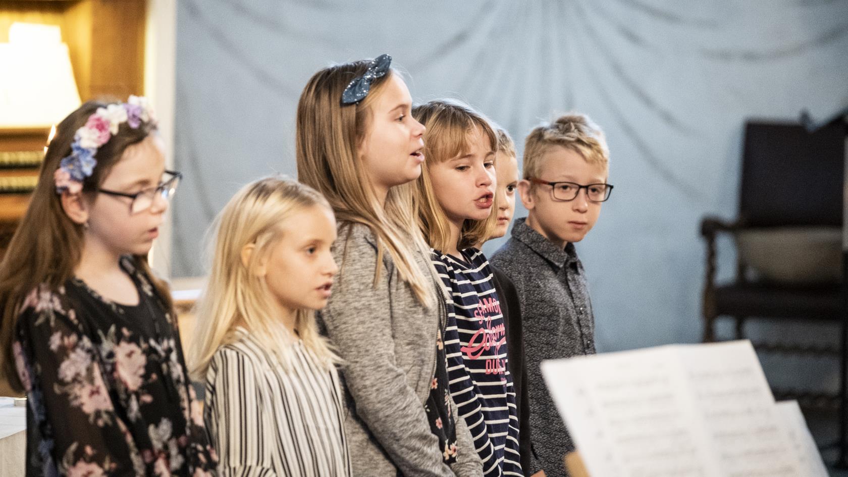 Några barn står bredvid varandra och sjunger framme i kyrkan.