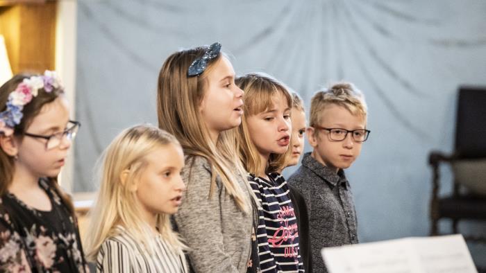 Några barn står bredvid varandra och sjunger framme i kyrkan.