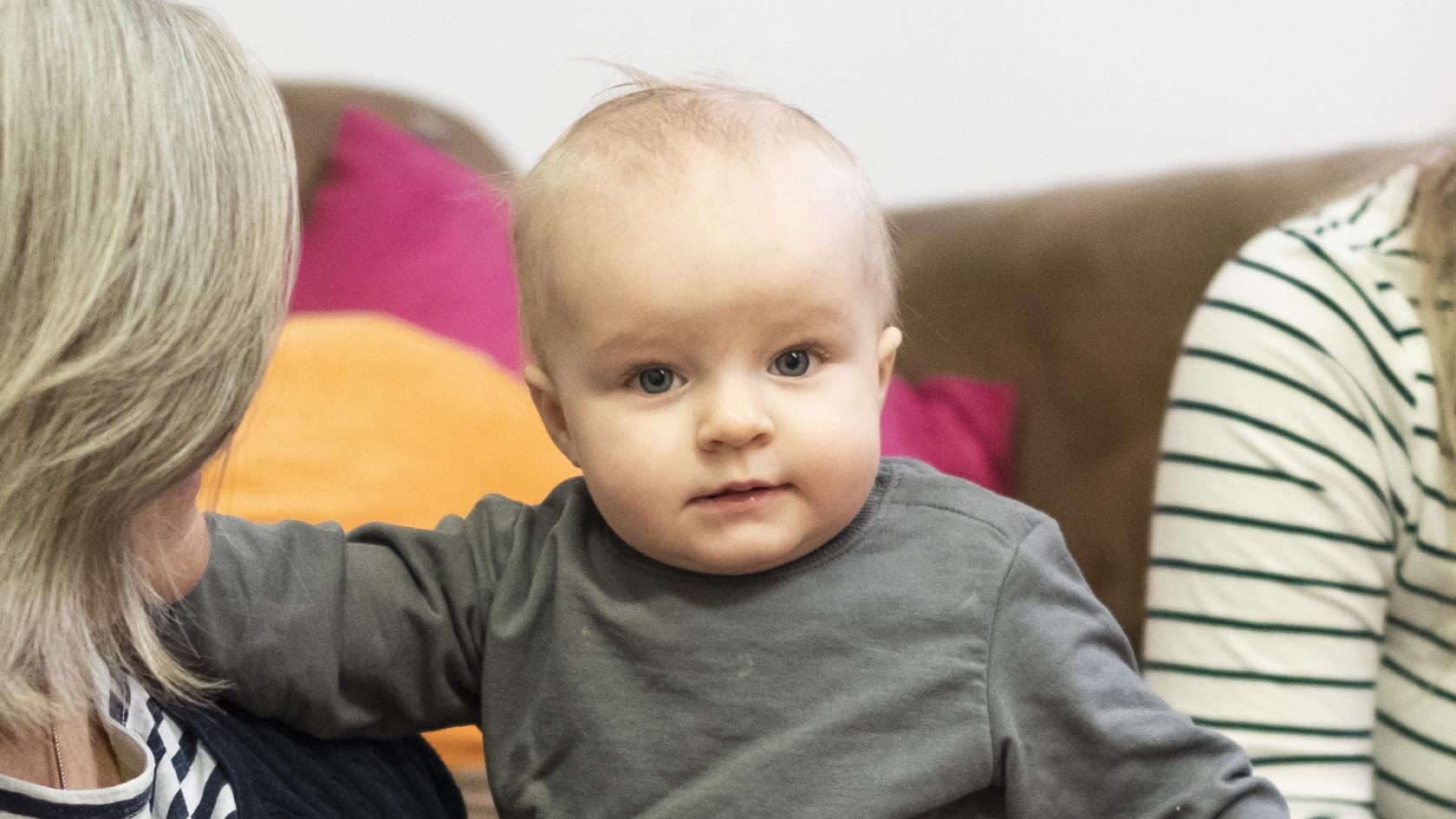 Två kvinnor sitter på golvet med ett litet barn.