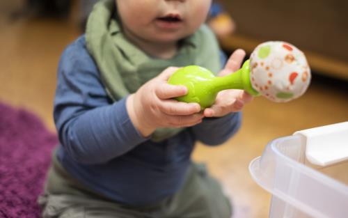 Ett litet barn håller i ett grönt leksaksinstrument.