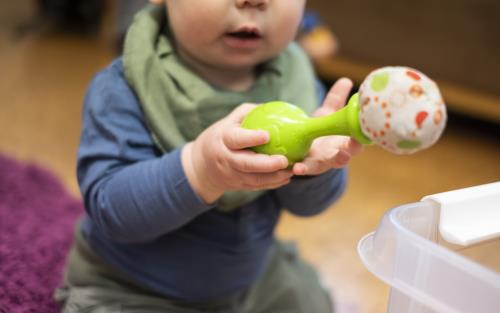Ett litet barn håller i ett grönt leksaksinstrument.