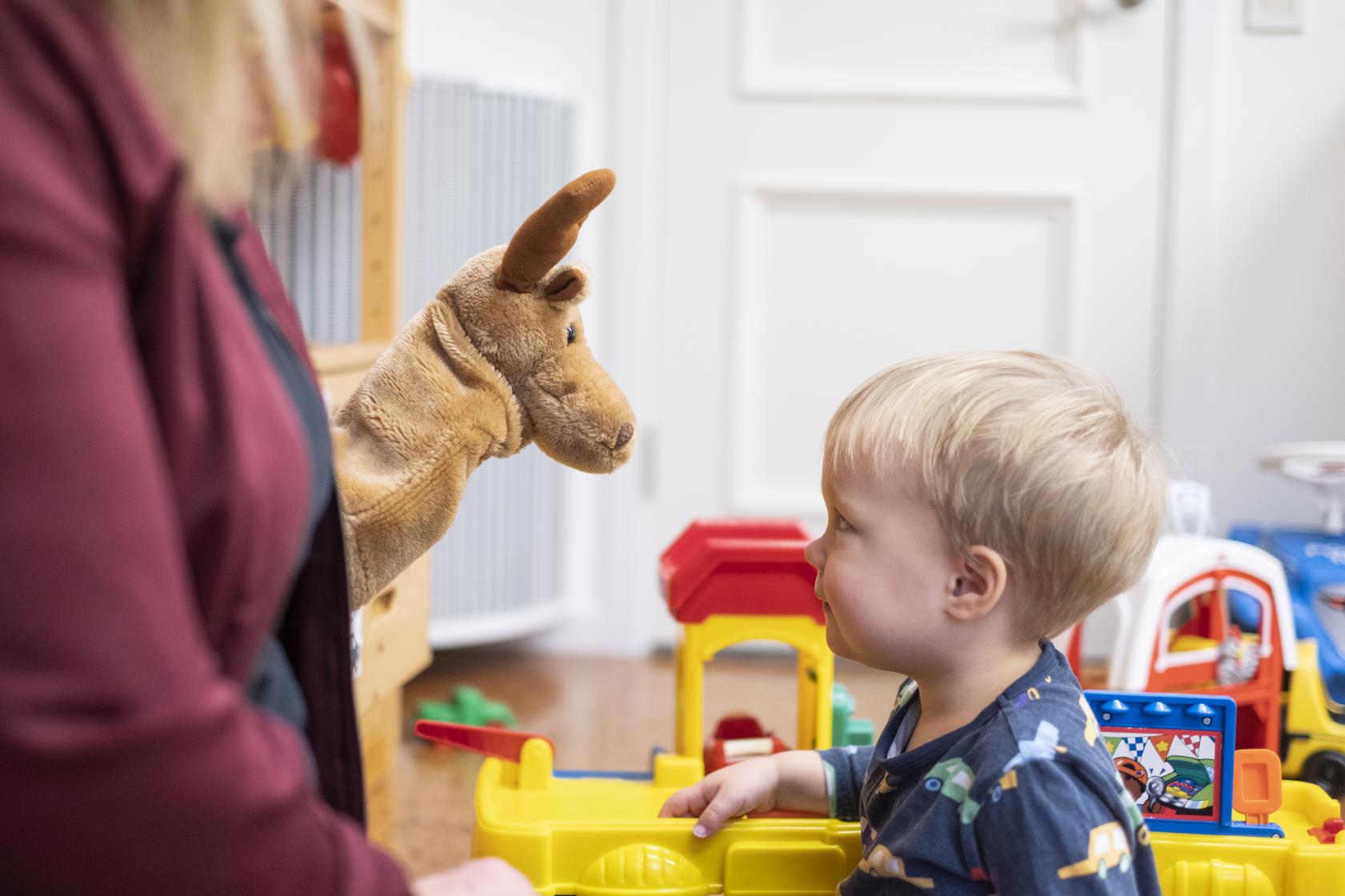 Ett barn tittar fascinerat på en handdocka som föreställer en älg.