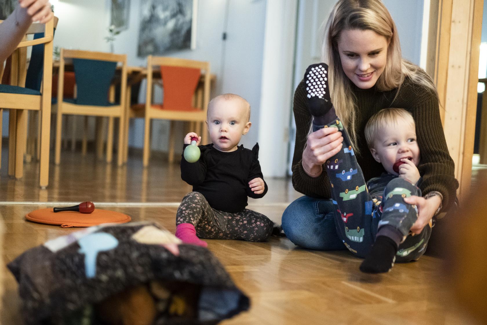 Några mammor sitter på golvet med sina bebisar.