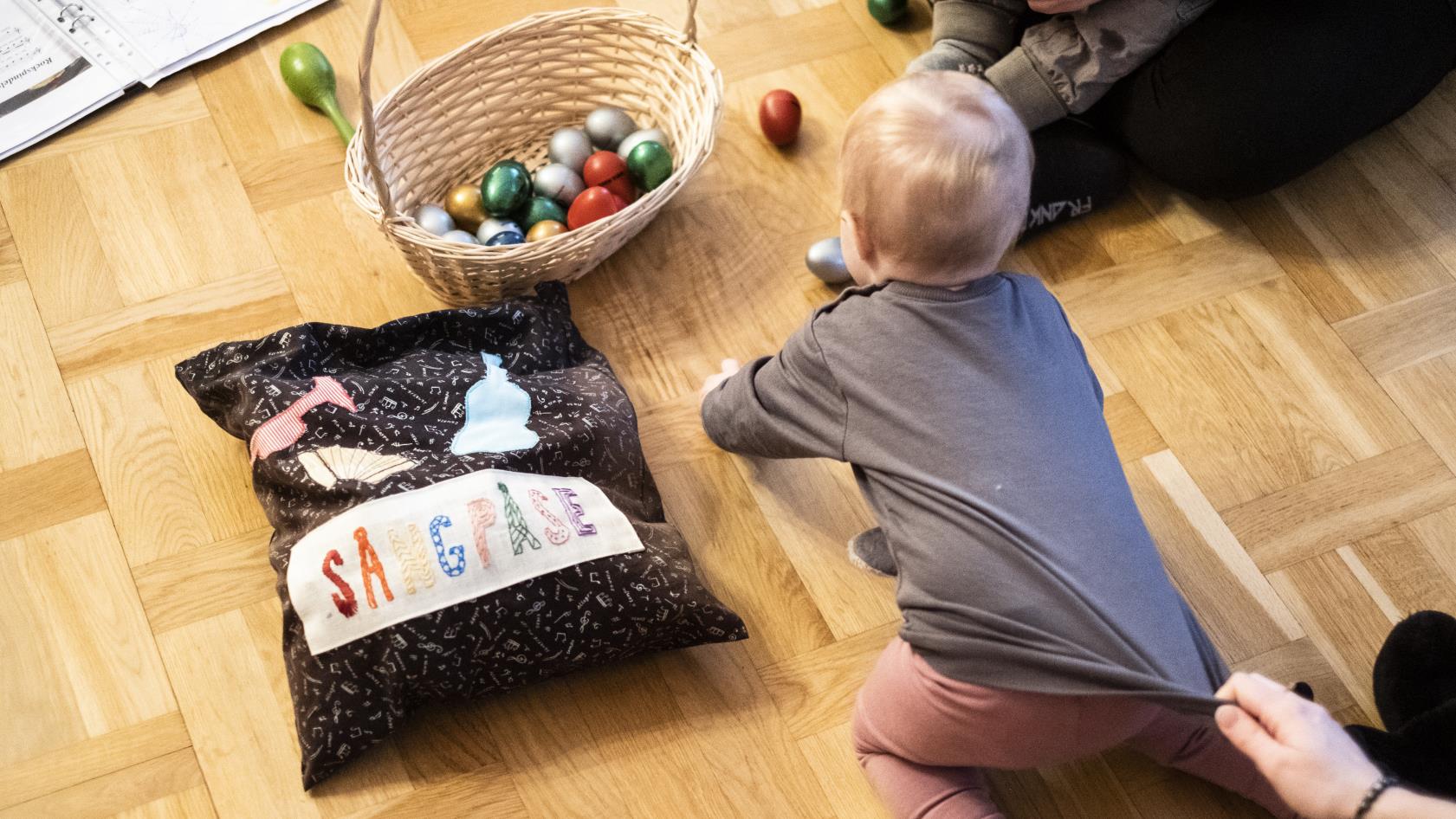 Några mammor sitter på golvet med sina bebisar.