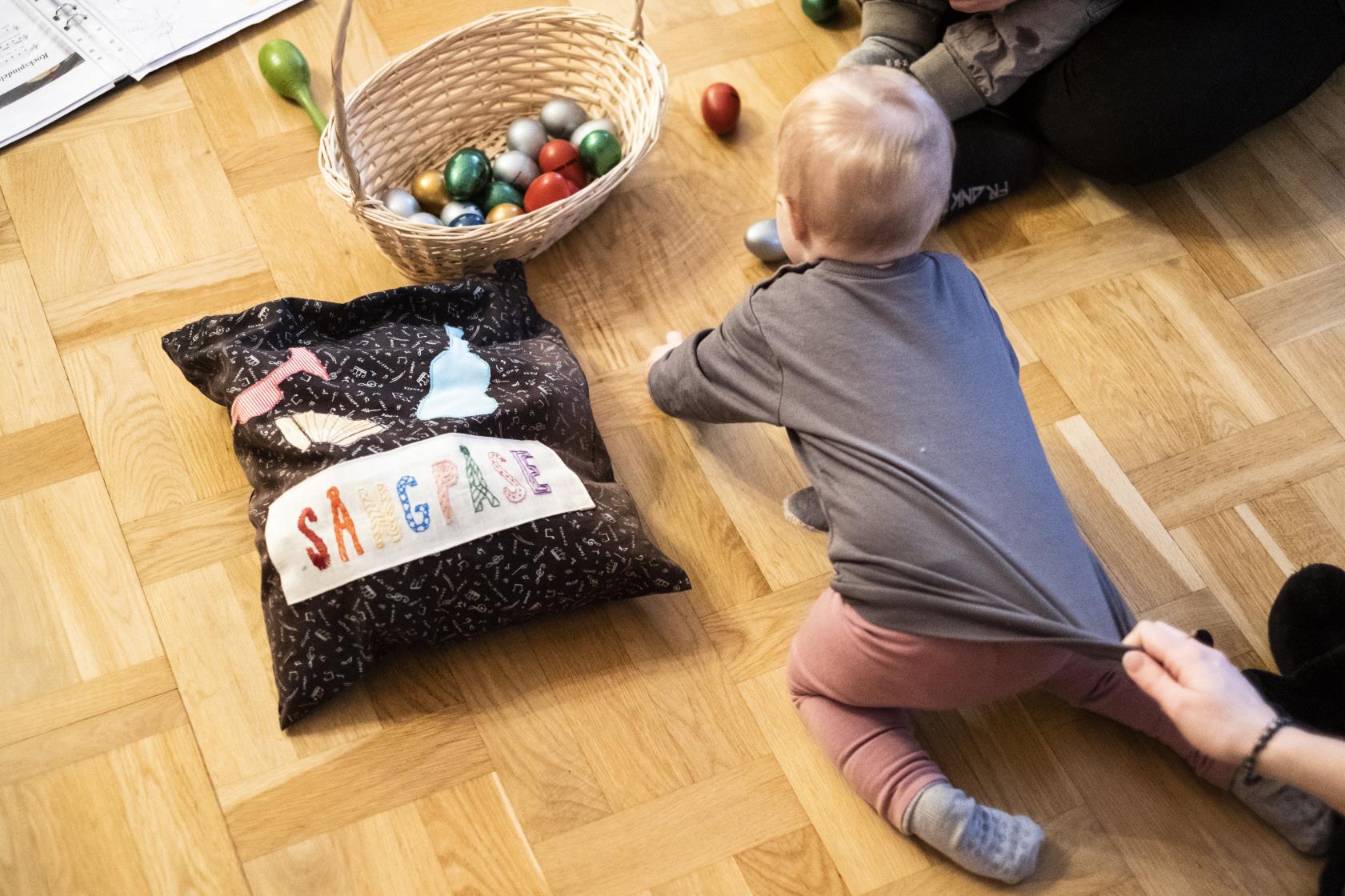 Några mammor sitter på golvet med sina bebisar.