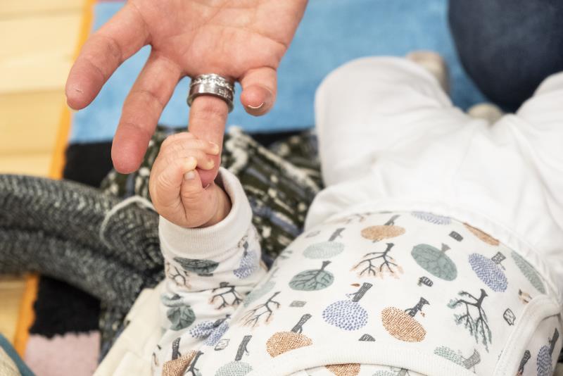 En bebis har gripit tag i en vuxens ringfinger.