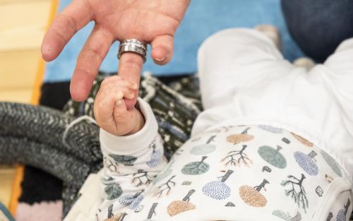 En bebis har gripit tag i en vuxens ringfinger.