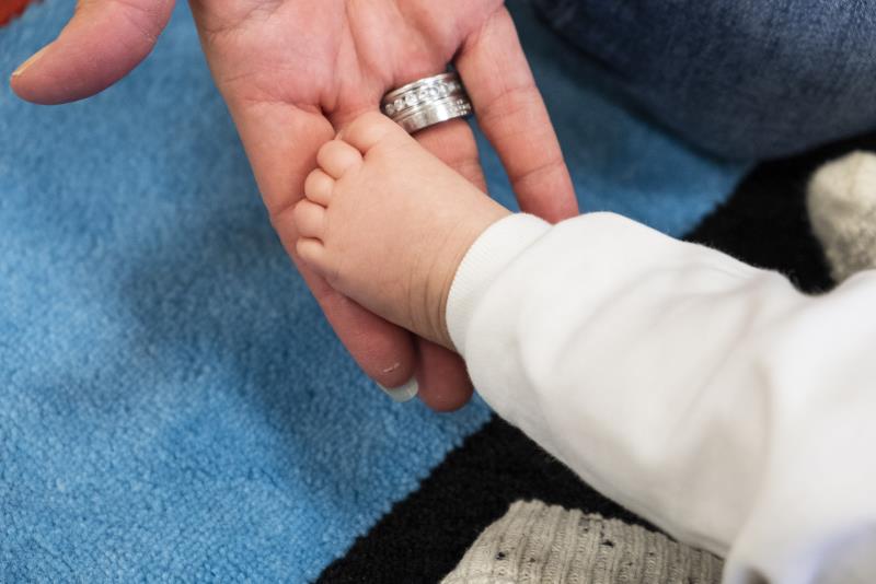 En vuxen hand lyfter en bebis fot.