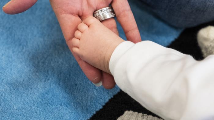 En vuxen hand lyfter en bebis fot.