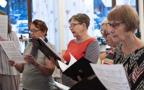 Några äldre kvinnor med notblad i händerna sjunger tillsammans.