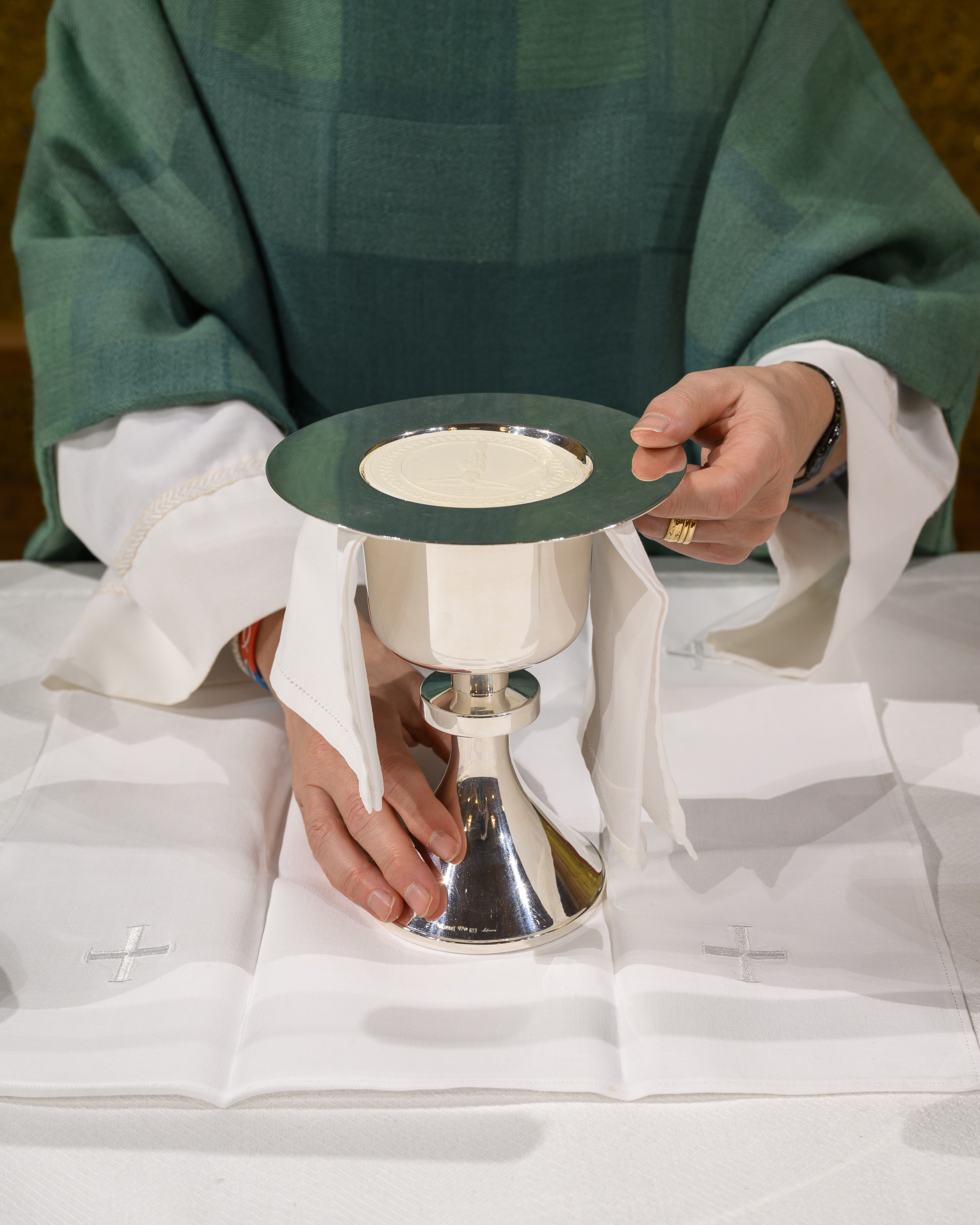 En präst i grön kåpa förbereder nattvarden.