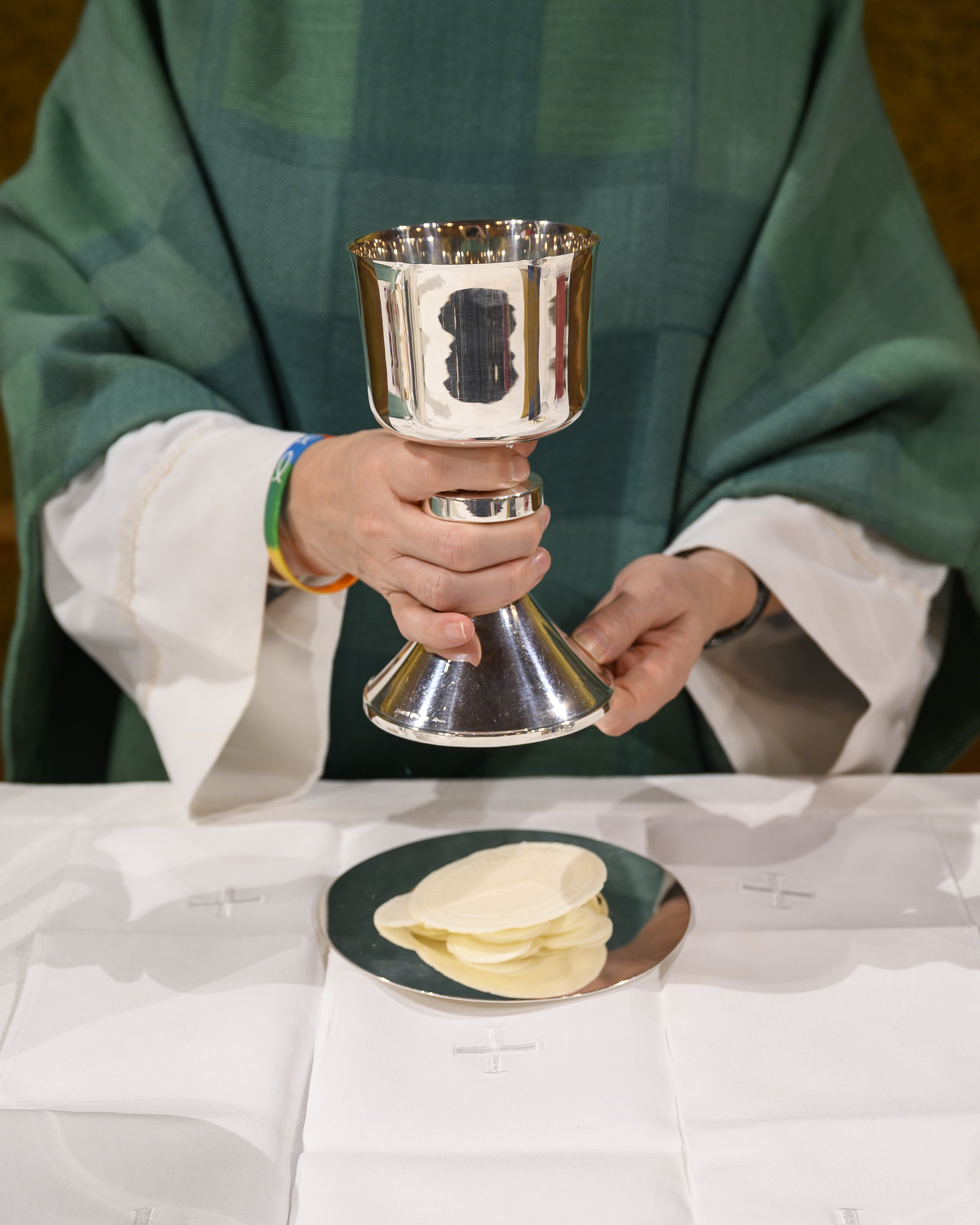 En präst i grön kåpa förbereder nattvarden.