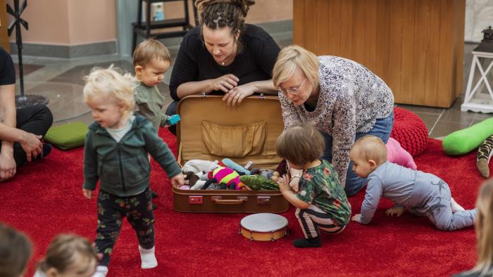 Några barn tittar ner i en resväska med gosedjur som fröknarna öppnat.