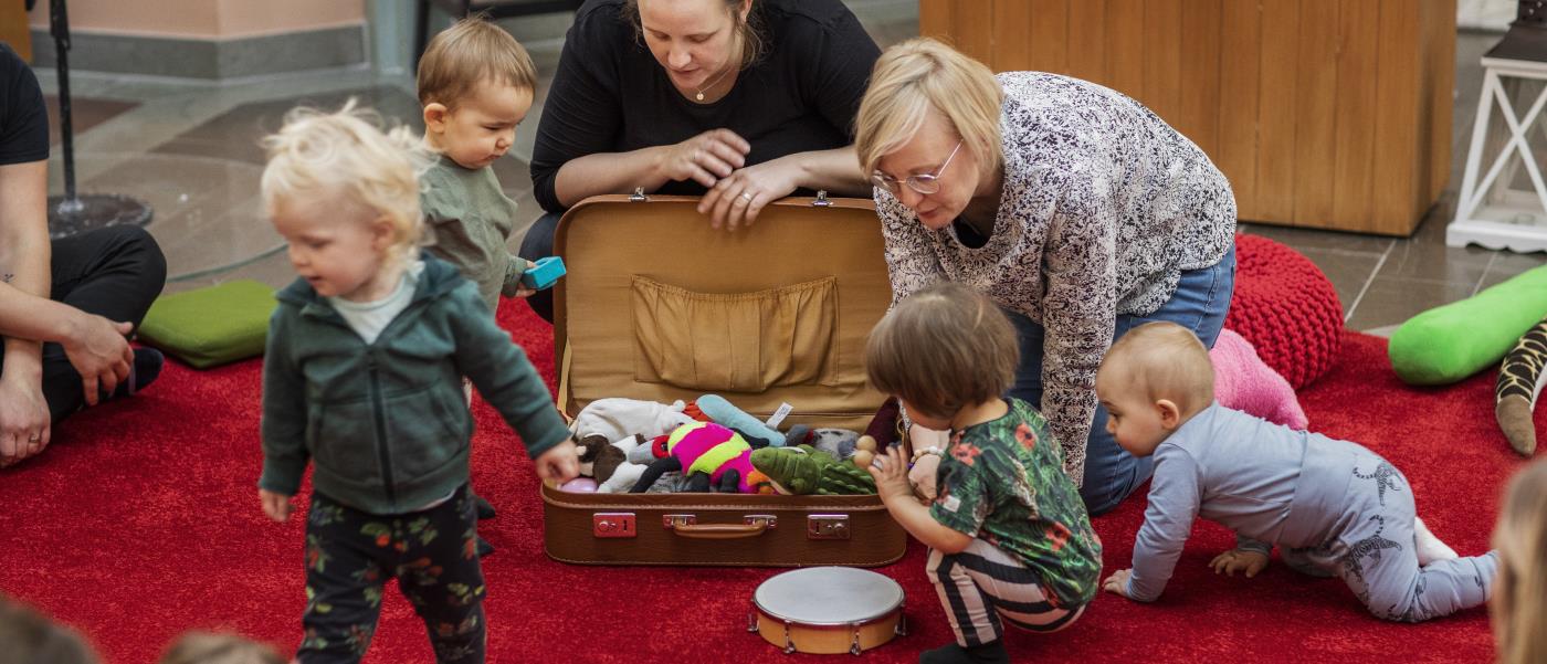 Några barn tittar ner i en resväska med gosedjur som fröknarna öppnat.