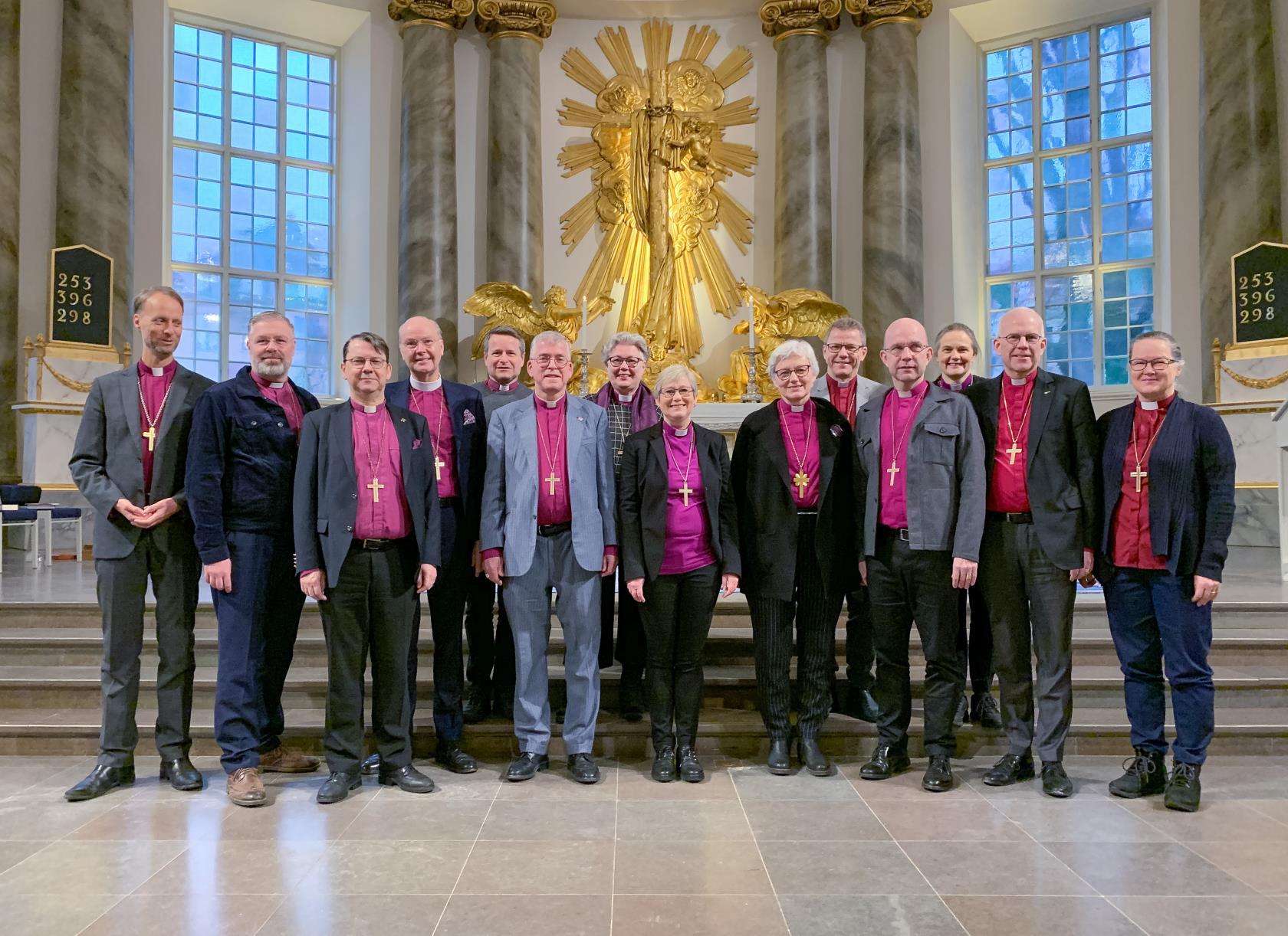 En grupp manliga och kvinnliga biskopar står i kyrkan och ler mot kameran.