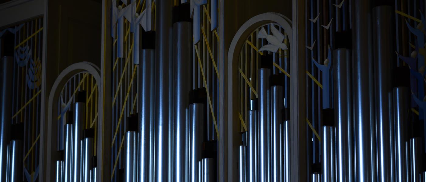 Solljus reflekteras i en kyrkorgels pipor.