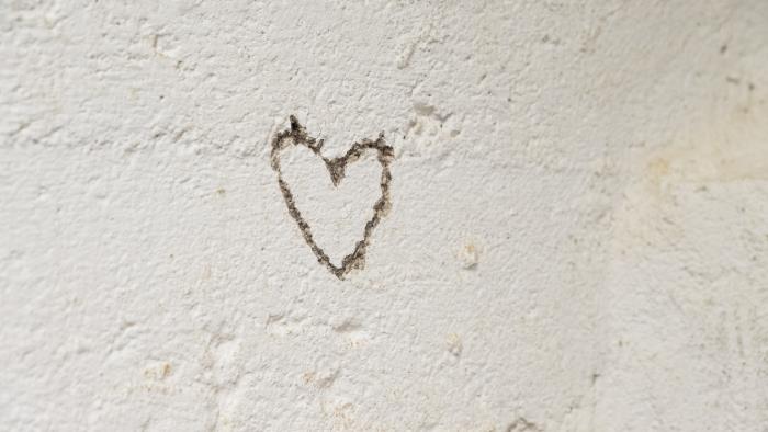 Ett hjärta inristat i en vit stenvägg.