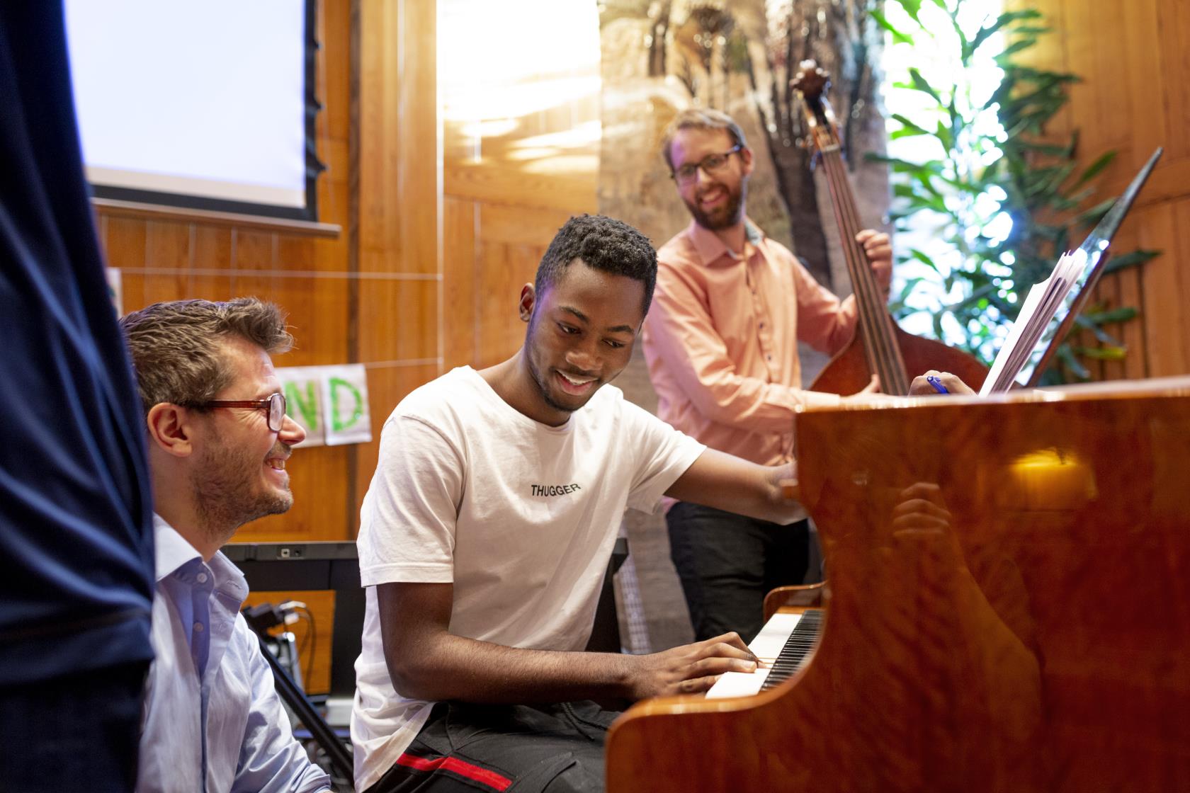 Tre män spelar piano och kontrabas tillsammans.