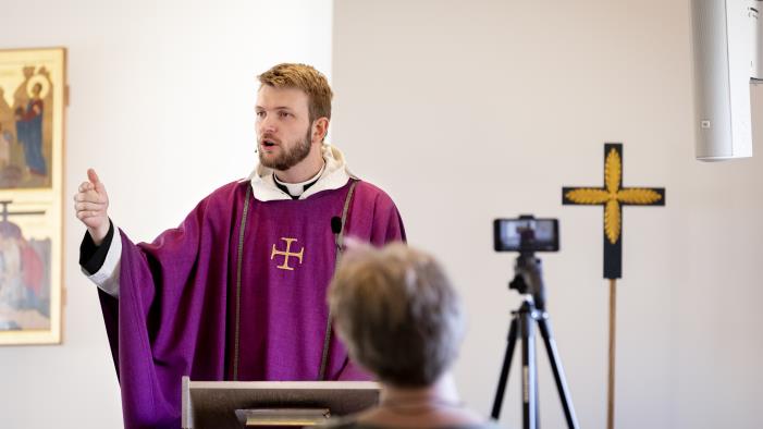 En präst predikar framför en kamera som filmar för direktsändning på webben.