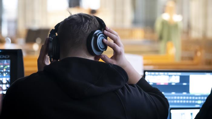 Några ljud- och bildtekniker sitter och jobbar i en bänkrad under inspelningen av en mässa i Uppsala domkyrka.