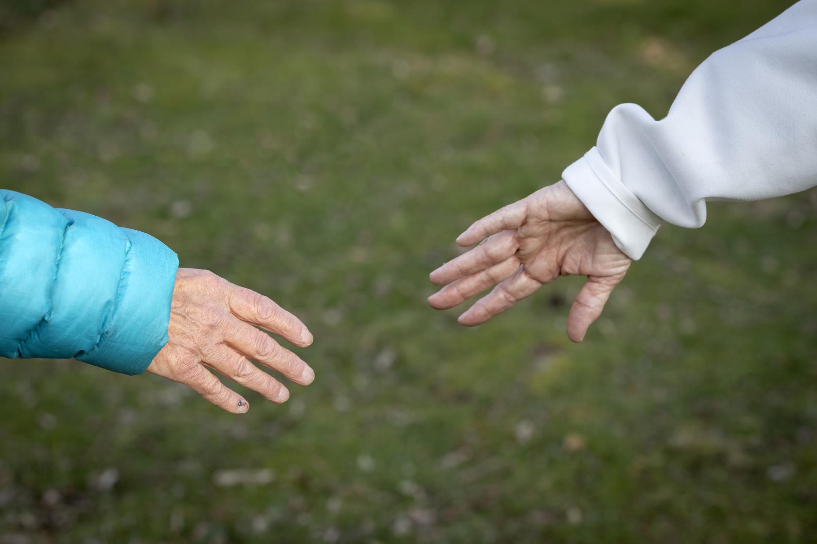 Två äldre personer vars händer möter varandra.