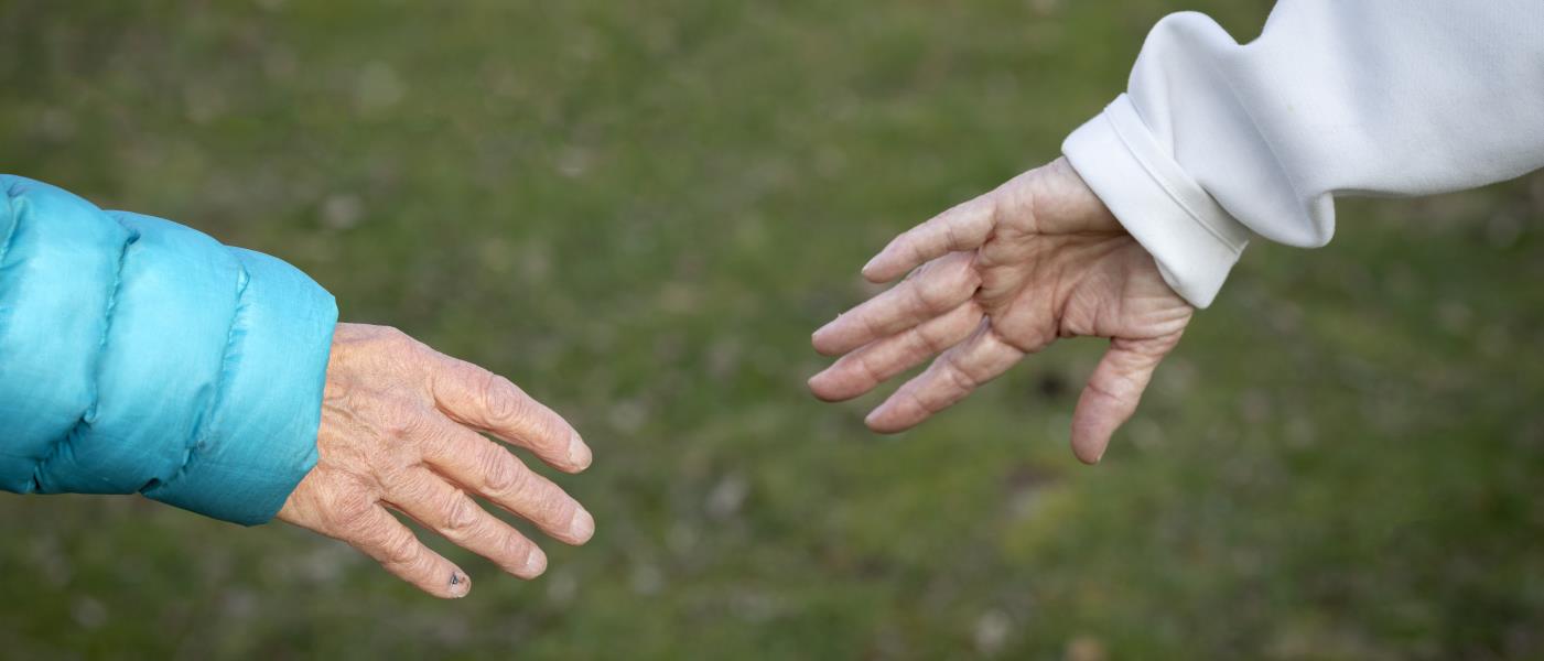Två äldre personer vars händer möter varandra.